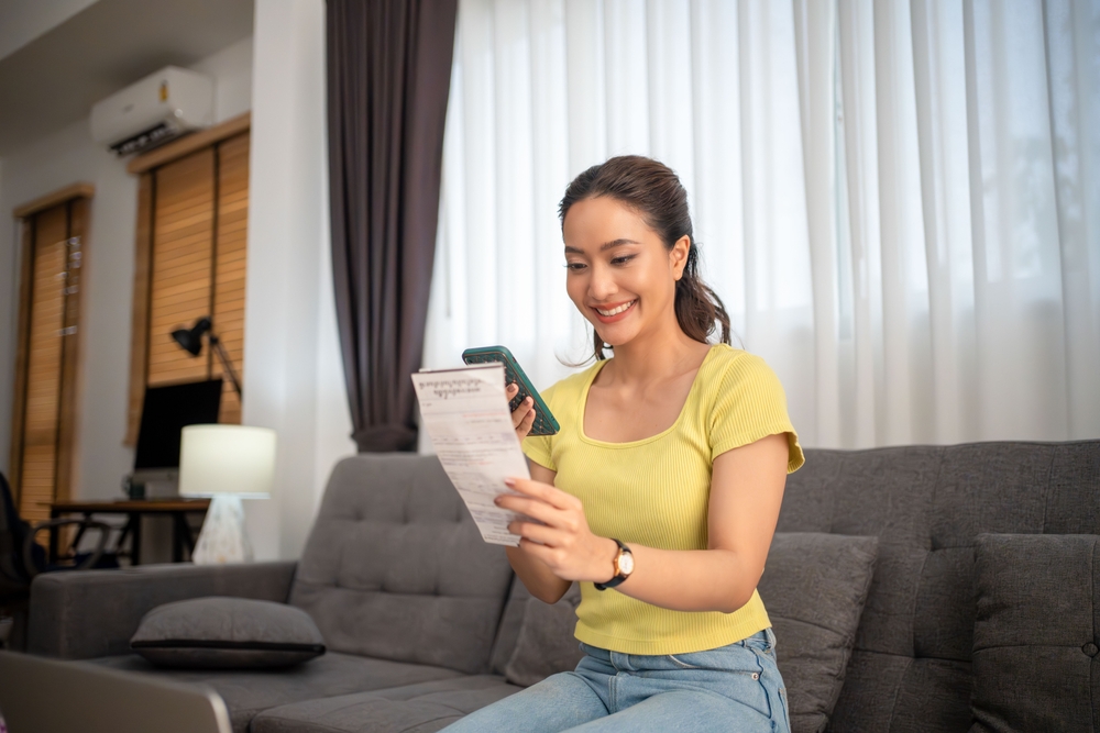 Asian woman using mobile phone for application QR code payment bill at home